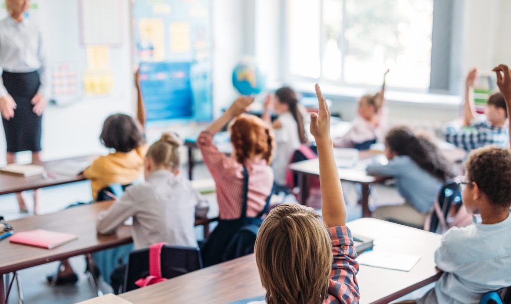 pupils raising hands on lesson to answer teacher question